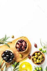 Olives in wooden bowls and Olive oil in the bottle at white table.