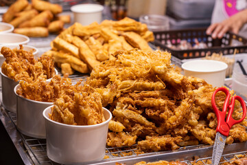 Vibrant golden-brown deep-fried street food snacks: crispy enoki mushrooms and fritters at a bustling Bangkok Chinatown night market. Perfect for a quick, delicious bite.