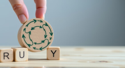 Hand holding wooden block with green recycling symbol, placed next to other wooden blocks on light wooden surface, symbolizing sustainability and eco friendly practices