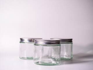 Three clean glass jars with silver lids arranged on a white surface, perfect for storage, crafting, or branding projects.