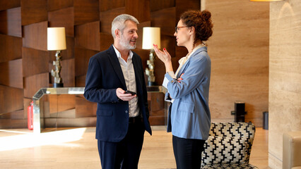 Business people engaging in a professional discussion in a modern office lobby setting, collaborating and networking