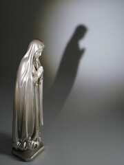Serene Virgin Mary statue casting a shadow of prayerful devotion, a symbol of faith, hope, and spiritual reflection in soft, contemplative light