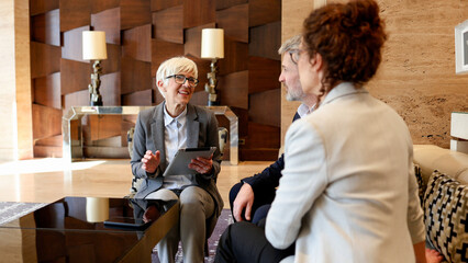 Diverse business professionals having a conversation, collaborating on a project in a contemporary workspace lobby interior