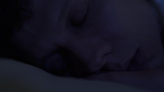 Man dreaming deeply at night, eyes moving under closed eyelids