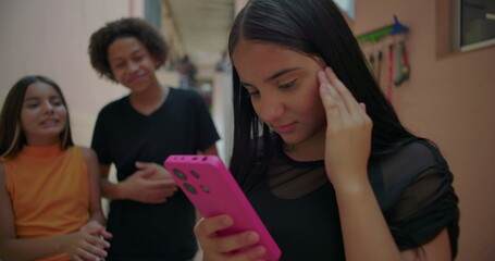 Teenager showing regret and frustration over social media post while friends laugh and point in suburban alleyway, expressive moment showcasing digital culture dynamics