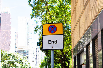 Do Not Enter or no entry blue and red cross aluminum square yellow and letters End on white sign city building background with trees and white sky. Regulatory signs for vehicular traffic sign.	