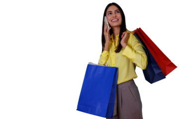 Woman standing with multiple shopping bags, talking on her mobile phone, expressing happiness and satisfaction during a shopping spree