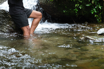Outdoor Adventure: Man Wading Through Clear Stream By Small Waterfall In Forest