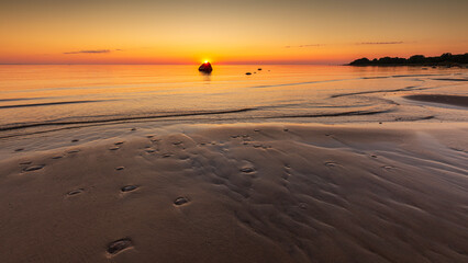Sunset seascape with rock on sandy beach in Lahemaa National Park, Estonia.