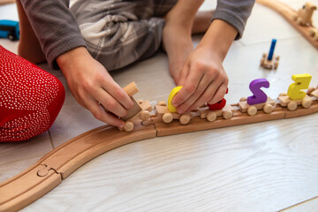 Obraz premium A boy and a girl are playing with a wooden toy train near a Christmas tree at home.