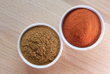 The paprika and cinnamon powder in a bowls on wooden table.