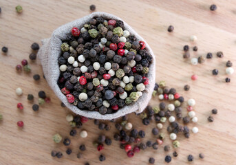 Mixture colored peppers in a canvas sack on wooden kitchen table.