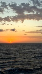 Fototapeta premium Stunning natural seascape showing warm colors of sunset above the horizon and calm waves of the sea.