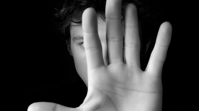 Young man with tousled hair raises hand in a dramatic gesture, showcasing emotions through expressive body language, as the camera gradually zooms in to capture the intensity of the moment