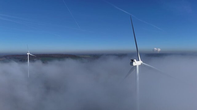 Une &eacute;olienne &eacute;merge au dessus d'un banc de brouillard, au mois de novembre, en automne, sur un beau ciel bleu. Parc &eacute;olien de Doncourt-les-Longuyon, en Meurthe et Moselle, Lorraine.