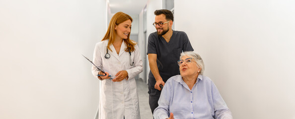 Doctors consulting with senior woman on wheelchair about recovery and medical progress in hospital...