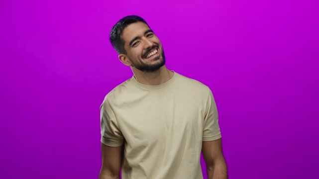 Young man shows playful expression against vibrant pink wall, embodying youthful charisma and spontaneity with a charming smile.