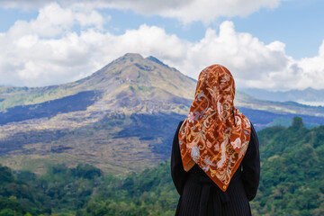 Woman in hijab contemplating mount batur bali volcano landscape