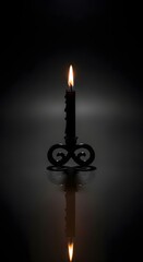 A single black candle in a decorative holder, lit and casting a warm glow against a dark, moody background, with its reflection visible below