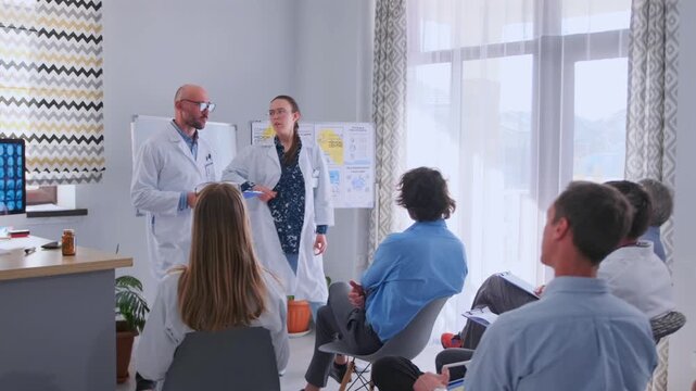 Male and female physicians in white coats stand in front of seated colleagues, giving lecture about new medicines and neurosurgical techniques during hospital seminar.