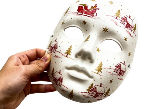 Hand holding a white ceramic mask decorated with a festive christmas village scene isolated on transparent background