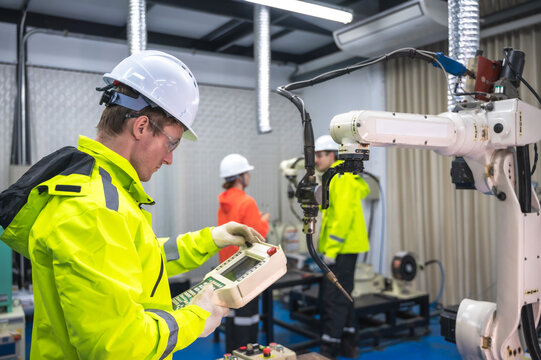 Male robotic engineer and teammates working with robot arm in innovation artificial intelligent learning center