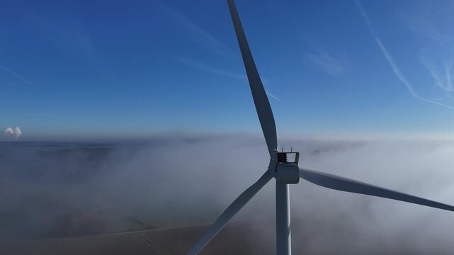 Une &eacute;olienne &eacute;merge au dessus d'un banc de brouillard, au mois de novembre, en automne, sur un beau ciel bleu. Parc &eacute;olien de Doncourt-les-Longuyon, en Meurthe et Moselle, Lorraine.
