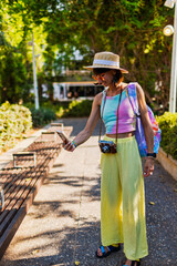 Stylish tourist taking photos of city center landmarks with her smartphone. Portrait of happy...