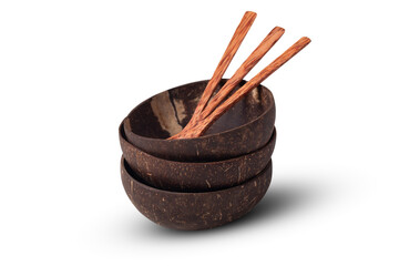 Three dark brown, handmade, and polished coconut shell bowls stacked together with three small wooden spoons, isolated on a white background