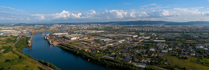 Fototapeta premium An expansive aerial view showcases an industrial city alongside a river, illustrating the complexity of urban development and the interplay between nature and human infrastructure.