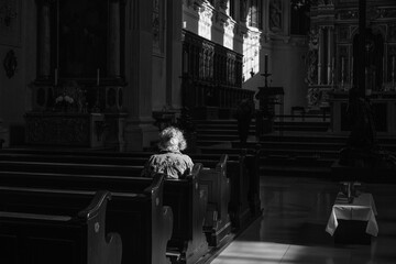 A ray of sunshine for eternity and blessing. Old woman sitting alone and praying in the church