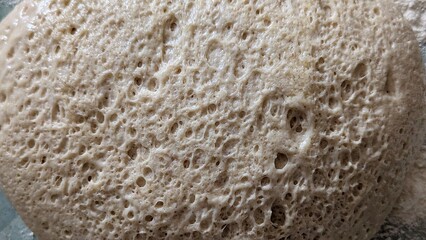 A macro top-down view of an active, bubbly sourdough starter, creating a porous abstract background of fermentation.