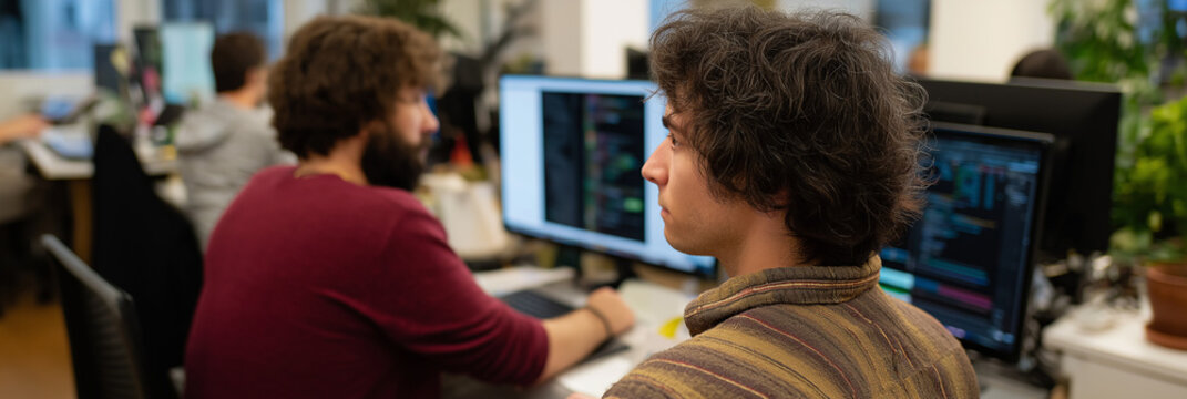 A collaborative office scene showing programmers engrossed in their work, portraying the essence of modern tech engagement and teamwork in a professional setting. - Powered by Adobe