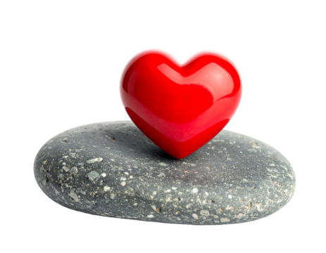 A glossy red heart rests atop a grey pebble against a contrasting dark background