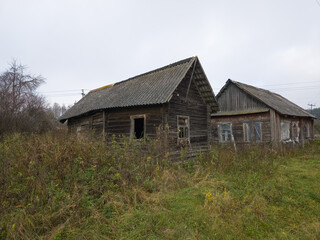 Abandoned wooden houses surrounded by overgrown grass in autumn  
