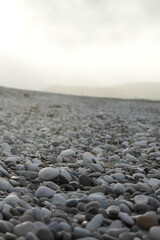 Close-up Of Smooth Grey And White Pebbles Stretching Across A Tranquil Beach Under A Hazy Sky In Towyn, North Wales, Uk.