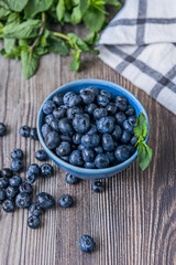 The blueberries appear arranged in a perfect circle on the light wood board, their spherical shape standing out against the linear grain