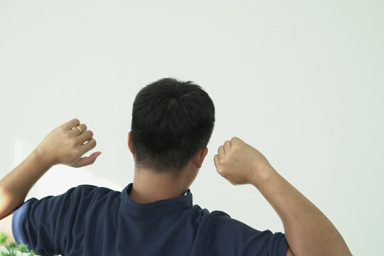 Young asian businessman is suffering pain on arm and neck, arthritis inflammation while working. he is massaging and stretching himself and doing exercise with his hands to relax and to relieve pain.