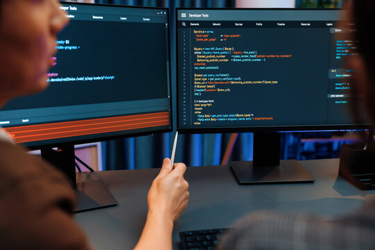 Smart IT developer looking at coding program application on computer screen of online website at back side, analyzing intelligent database system development on business marketing at office. Infobahn.