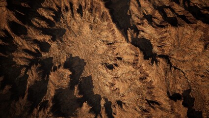 A vast expanse of jagged rocks and rugged terrain stretches across the landscape, illuminated by bright sunlight. Shadows play across the surface, highlighting the intricate textures of the earth.