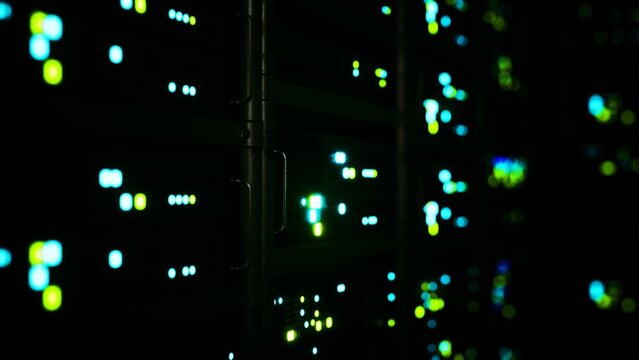 In a darkened room, rows of data servers come alive with colorful blinking lights, creating an atmosphere of advanced technology and digital connectivity as they process information rapidly.
