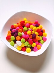 Vertical. Sweet candy. Colorful candies in a white plate.