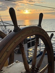 an antique ship's wheel at sunset at sea