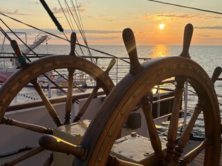 sunset at sea through an old ship's wheel
