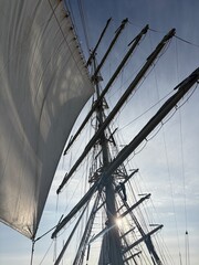 sun above the sails and masts of a tall ship