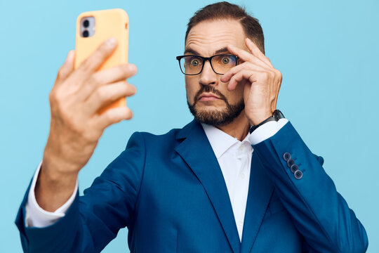A professional businessman on an isolated colored background, exuding focus and confidence as he uses a smartphone, showing determination and curiosity in the moment.