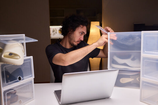 Individual systematically records shoe information on computer in workspace, Person carefully inputs sneaker details into spreadsheet within tidy home office environment