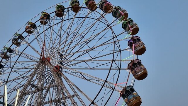 A large Ferris wheel with colorful cabins against a cloudy sky. This popular fairground attraction offers panoramic views, but may trigger acrophobia, the fear of heights.