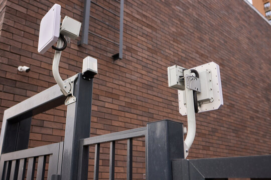 Urban security surveillance, Industrial style gate camera system, Surveillance units installed on brick structures, Perimeter monitoring with visible cables and brackets