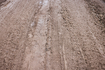 Rural muddy terrain, Uneven rural path with puddles, Challenging countryside trail with deep grooves, Rough dirt road featuring deep tire grooves and muddy patches